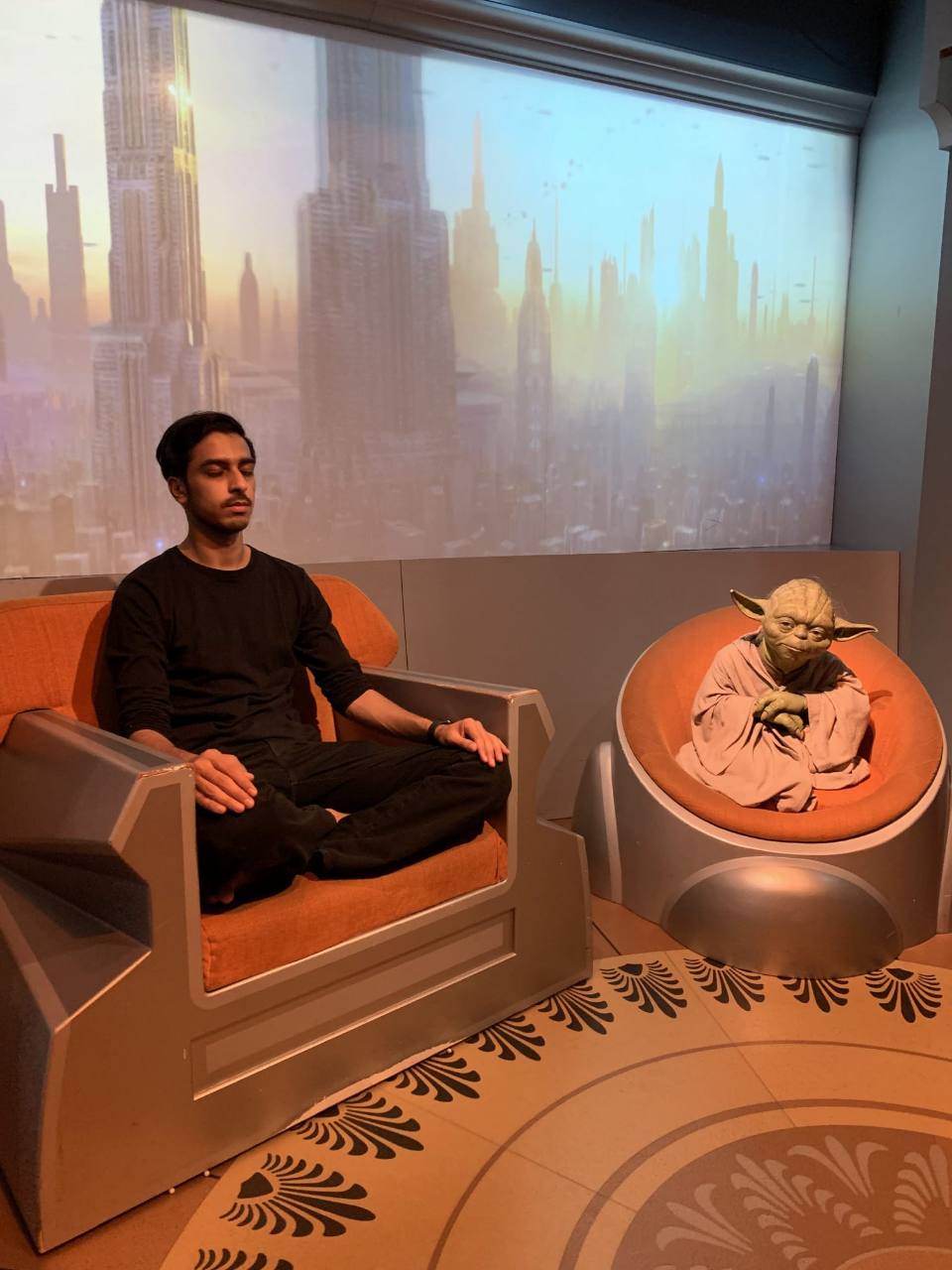Owais sitting with eyes closed beside a figure of Yoda